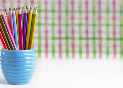五颜六色的铅笔在一个水罐在白色的课桌与拷贝空间到旁边模糊的背景为文本覆盖学校或教学