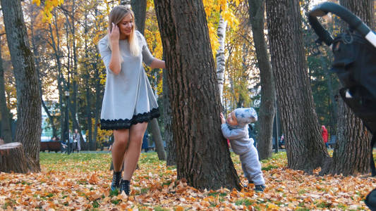 年轻的母亲和她的小宝贝在公园里。玩捉迷藏