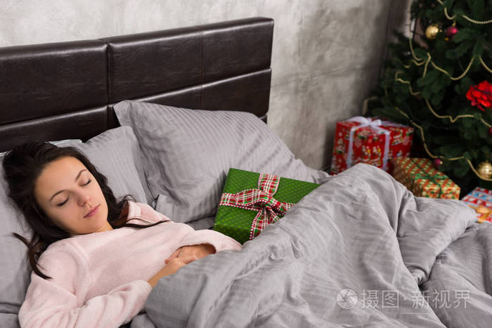 年轻漂亮的女人睡在床上和圣诞节本躺