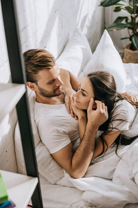 高角度的角度高兴的年轻夫妇放松和聊天在床上的早晨