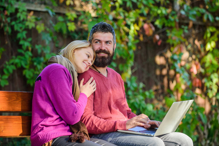 情侣在爱的笔记本消费内容。网上冲浪的概念。夫妇与笔记本电脑坐在公园自然背景。一起上网。家庭上网的有趣的内容