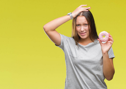 年轻的白种女人吃甜甜甜圈在孤立的背景强调与手在头上, 震惊与羞愧和惊讶的脸, 愤怒和沮丧。对错误的恐惧和不安