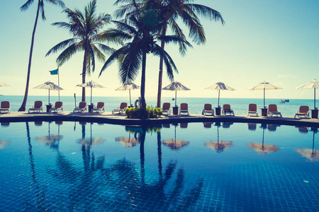 美丽的热带海滩和海与伞和椅子在游泳池附近在旅馆度假胜地为旅行和假期