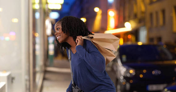 一天晚上, 黑人女子看着城市里优雅的橱窗展示购物
