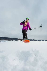 通过她的手机拍摄自拍照的滑雪板的年轻女子