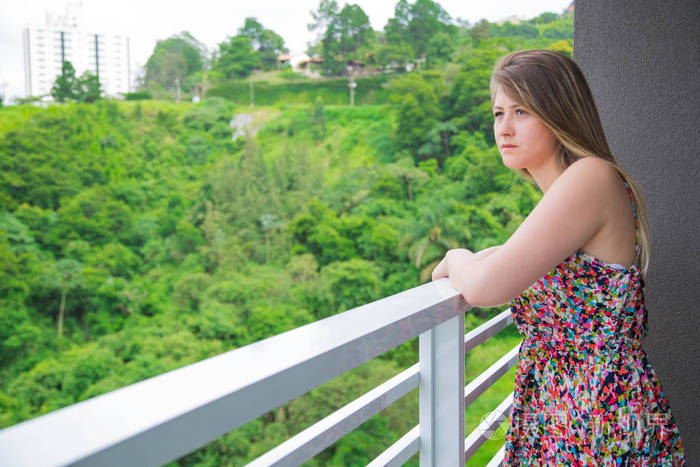 严重的年轻女人从阳台上看风景
