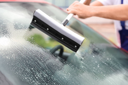 人用玻璃雨刷清洁挡风玻璃, 特写镜头。洗车服务