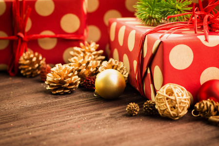 圣诞节和元旦节日的装饰, 金球, 五颜六色的冷杉锥和树枝, 木制的星星与两个礼物包裹在红色的纸与金色的圆圈在棕色木头背景。复制文