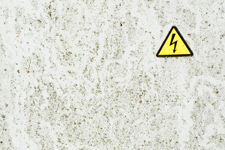 白色铁金属锈迹斑斑的油漆喷壁和黄色警告三角危险高压标志。背景介绍