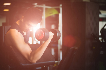 男子手持哑铃运动在健身房。健身肌肉身体与一套黑色重量在健身房背景。运动和健康的生活方式概念