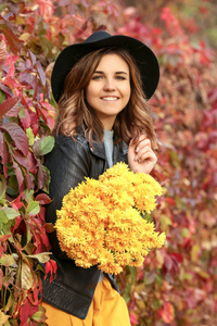美丽的年轻妇女与黄色花在秋天公园