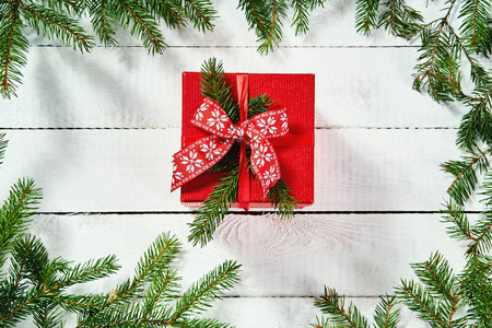 在一个古老的白色木桌与云杉的小树枝的红色圣诞礼物的顶部视图