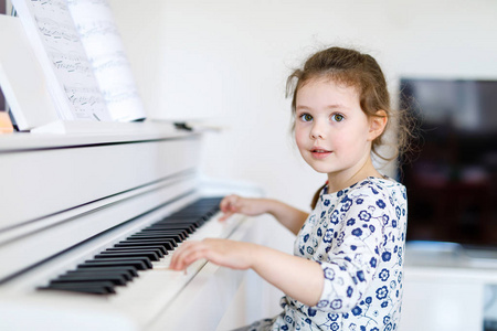 漂亮的小孩小女孩弹钢琴在客厅或音乐学校