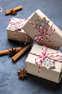 圣诞礼物或礼物盒包裹在牛皮纸与装饰在黑暗的背景。礼物装饰与圣诞曲奇