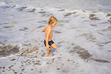 小男孩在海边的海岸线上玩耍