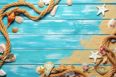 海绳索与海贝壳在海沙子在蓝色木背景。顶视图