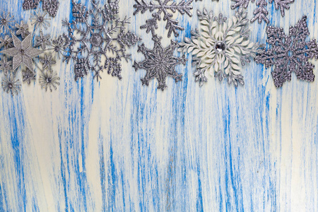 蓝色木制背景下的圣诞雪花。银色雪花的边界