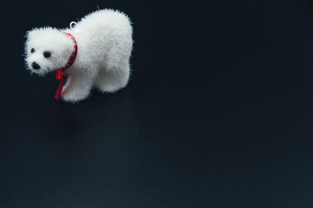 假日壁纸背景的白色北极熊玩具与红色衣领与花边隔离在黑色背景。复制空间