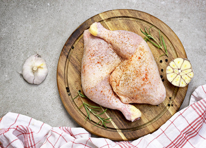 木制切菜板上美味的生鸡腿或鸡腿。大蒜和生肉的质朴准备场景