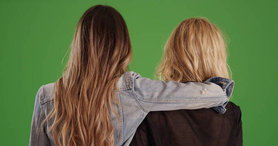 女性好友在绿色屏幕上相互牵制的后视