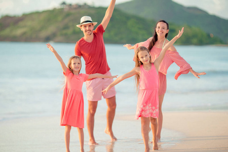 愉快的家庭与孩子在海滩漫步在日落