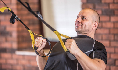 强壮的肌肉发达的男子在健身房或健身中心使用 trx 设施锻炼