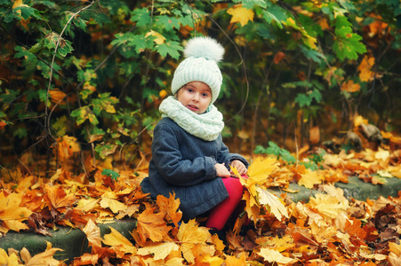 一个小女孩在公园散步时的秋天画像。戴帽子外套和围巾的儿童