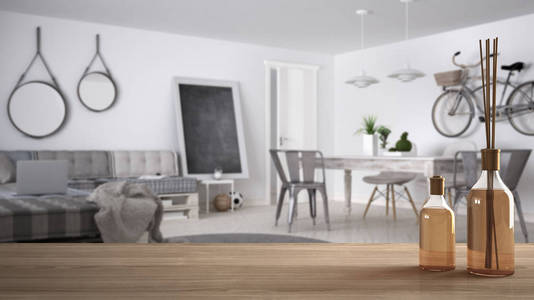 木制桌面或货架与芳香棒瓶在模糊的现代现代客厅在斯堪的纳维亚风格, 白色建筑室内设计