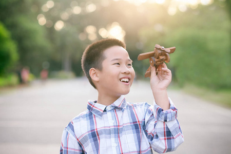 快乐和微笑的小男孩玩玩具飞机在公园户外