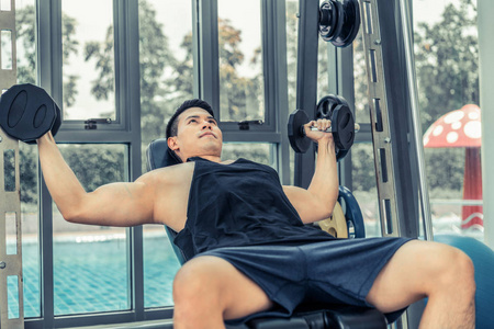 肌肉的男人健美在健身房训练哑铃。健康的生活方式和健美理念