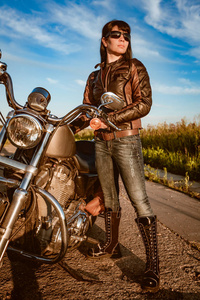骑自行车的女孩，在一件皮夹克和坐在摩托车上的太阳镜