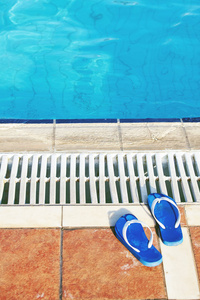 游泳池里有两双蓝色凉鞋。假期理念