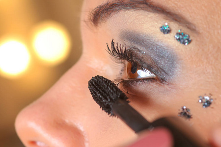 年轻漂亮的女人用毛笔在眼睛上用睫毛膏化妆