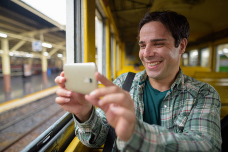 波斯游客坐在火车上, 用手机
