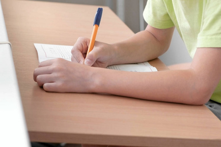 学校的孩子学会写字母坐在桌子旁。特写男孩的手