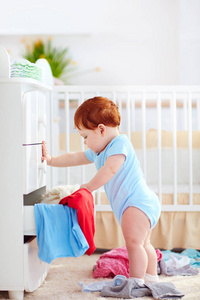 有趣的婴儿婴儿从梳妆台上在家里扔掉的衣服
