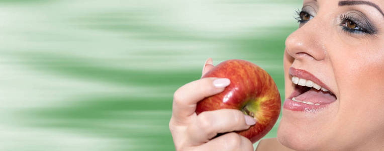 漂亮的女人咬一个苹果在模糊的背景