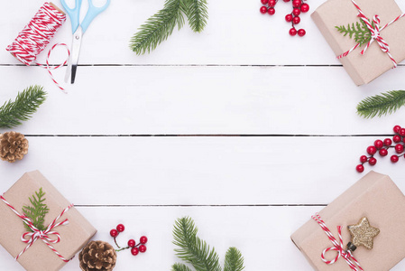 圣诞节背景概念。圣诞礼品盒的顶部视图与云杉分支, 松果, 红色浆果和响铃在白色木桌背景