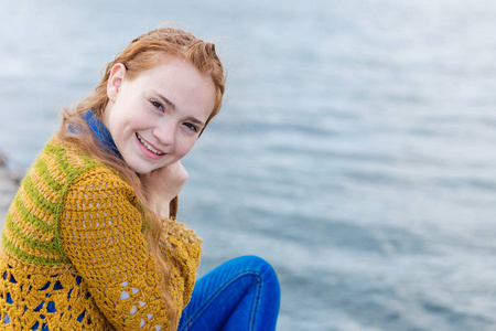 红头发的女孩坐在海边上的雀斑
