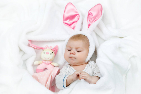 可爱可爱初生女婴在复活节兔子服装和耳朵。可爱的孩子玩毛绒兔子玩具。节日概念