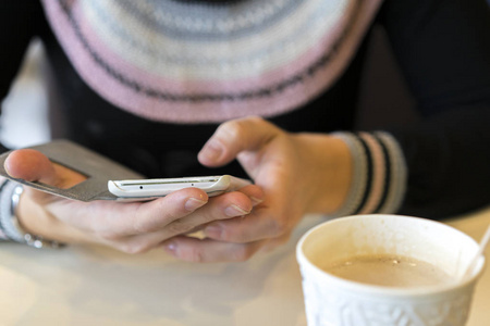 一个女孩坐在咖啡馆里时正在使用智能手机。选定的焦点