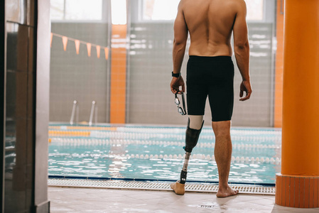 运动员的裁剪镜头与人工腿站在室内游泳池前