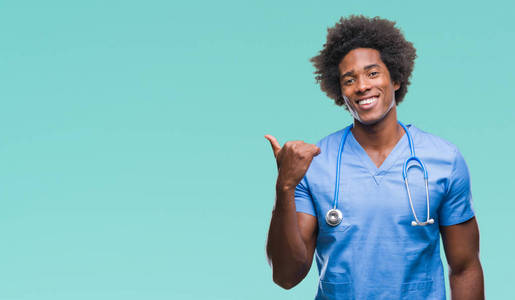 非裔美国外科医生在孤立的背景微笑与愉快的面孔看和指向边用拇指