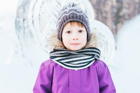 一个穿着冬衣的男孩在冰雕。在冬季, 马奇克在一个雪镇的公园里散步