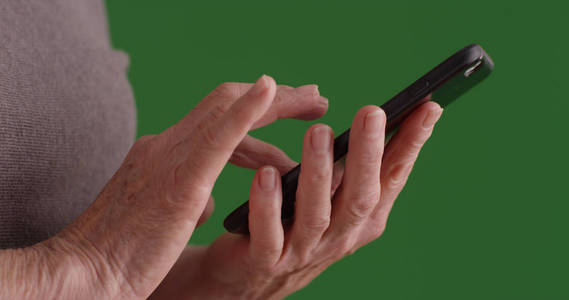 在绿色屏幕上使用智能手机关闭老年女性手的镜头