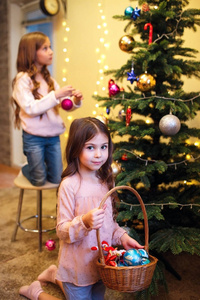 圣诞快乐, 节日快乐。两个可爱的小女孩正在装饰家里的圣诞树