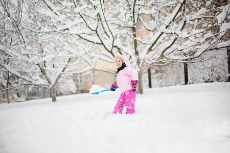 这孩子在冬天玩雪。一个穿着鲜艳夹克头戴针织帽子的小女孩, 在冬季公园里捕捉雪花过圣诞节。孩子们在被雪覆盖的花园里玩耍和跳跃