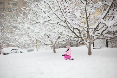 这孩子在冬天玩雪。一个穿着鲜艳夹克头戴针织帽子的小女孩, 在冬季公园里捕捉雪花过圣诞节。孩子们在被雪覆盖的花园里玩耍和跳跃