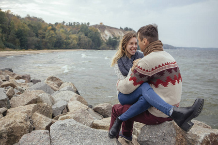 快乐周到夫妻坐在一块岩石上海滩附近大海拥抱