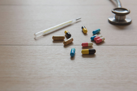 特写药物胶囊和听诊器和汞在木桌上。医学的概念